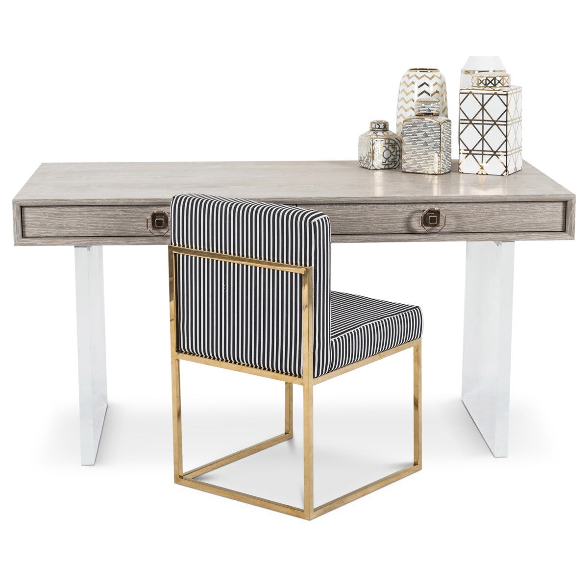 Slim two-drawer desk with a gray aged wood finish and solid white sides behind a desk chair with a polished brass base and black and white striped upholstery.
