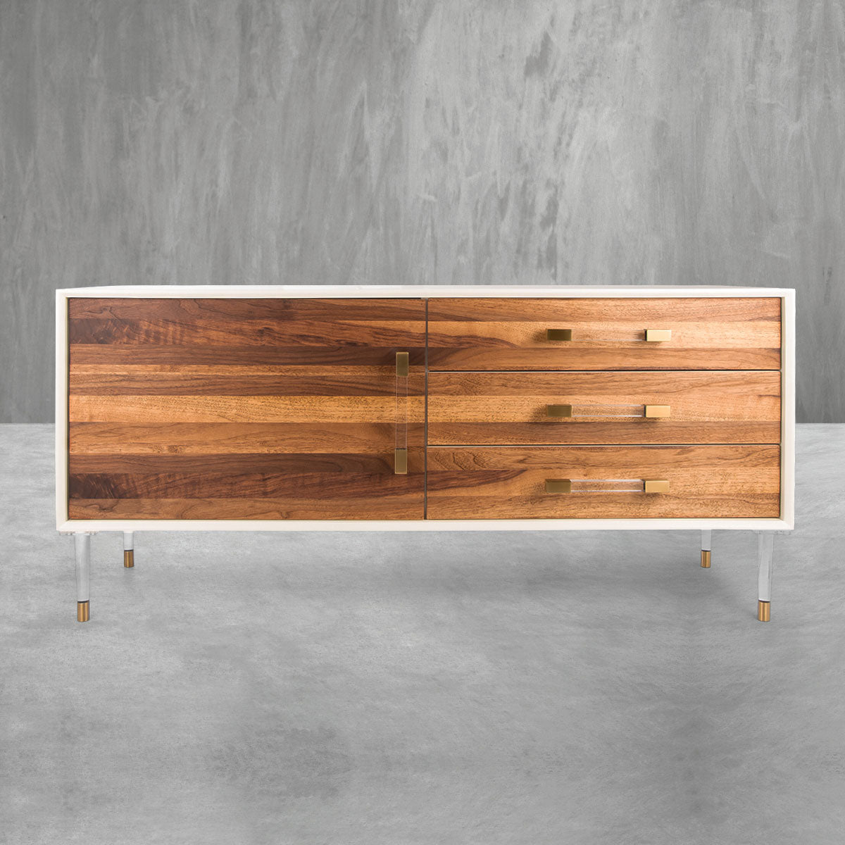 Modern credenza with a white frame, white and brass legs, three drawers with brass pulls, a single cabinet door with a Lucite pull and a medium-tone wood plank facade on all door and drawer faces.