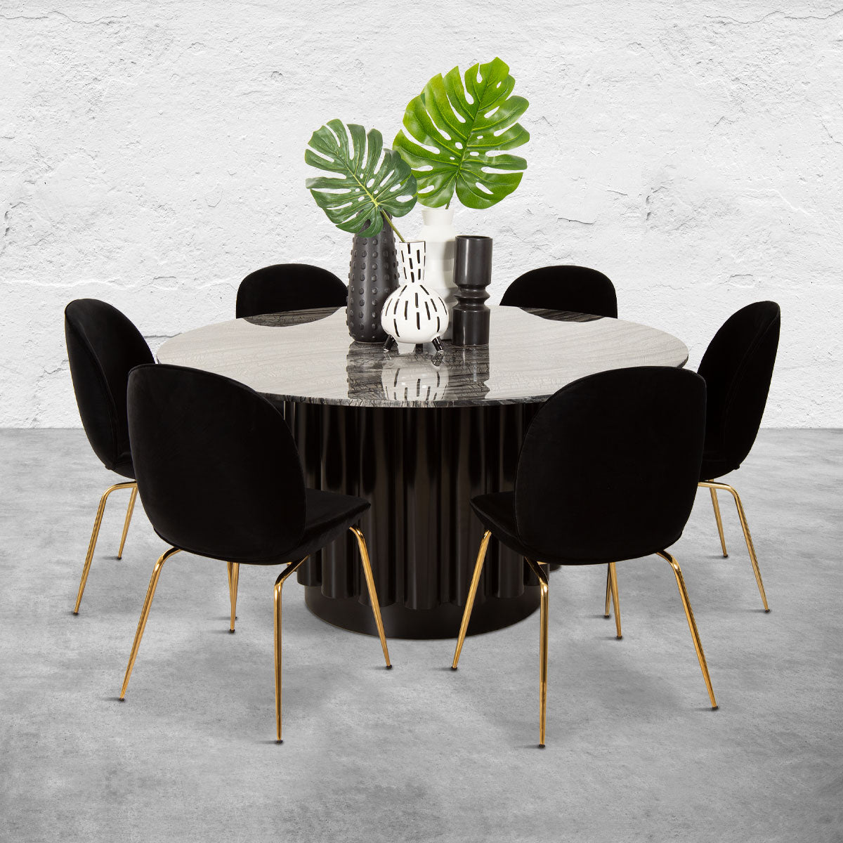 Round dining table with a black columnar base, a black marble top and six black upholstered chairs with brass legs.