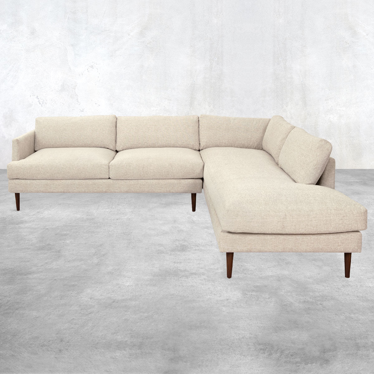 Two-piece sectional sofa with a chaise end, overstuffed pillow back, brown cone legs and light beige upholstery.