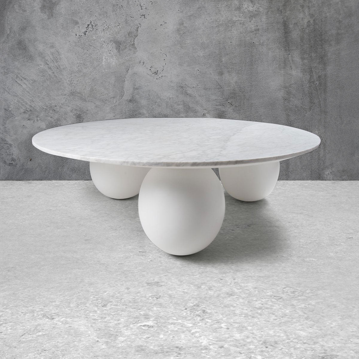 Modern round coffee table with three spherical legs in white and a light marble top.