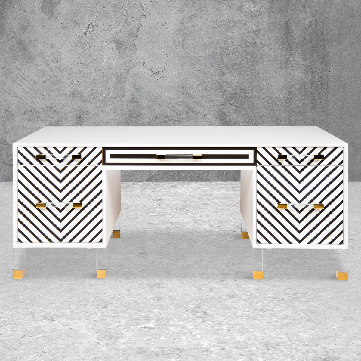 White modern executive desk with side and center drawers, clear acrylic feet, gold hardware and a black zigzag pattern on the front.